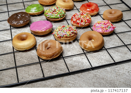 A tray of assorted mini donuts with sprinkles and frosting A tray of assorted mini donuts with sprinkles and frosting 117417137
