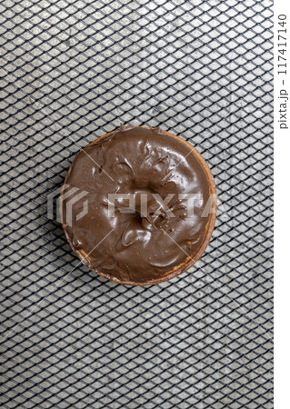 A chocolate mini donut sits on a metal mesh A chocolate mini donut sits on a metal mesh 117417140