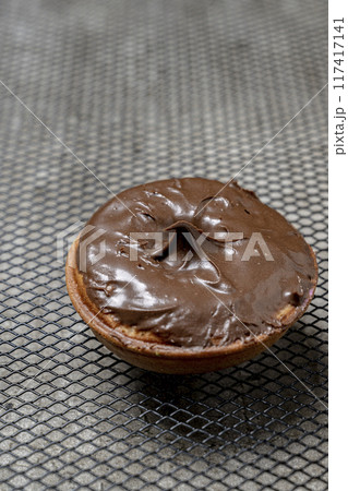 A chocolate mini donut sits on a metal mesh 117417141