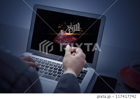 A man is using a laptop to pay for something with a credit card 117417742