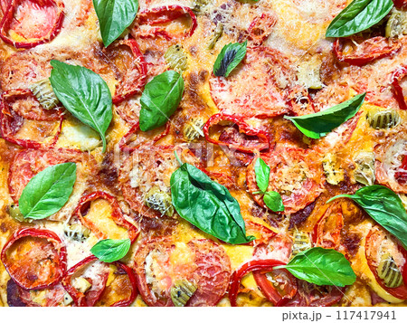 Background of traditional Italian pizza with ham, cheese, tomatoes and basil close-up.  117417941