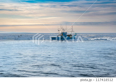 オホーツク海、夕焼けに染まる漁船、流氷が流れてくる オホーツク海、夕焼けに染まる漁船、流氷が流れてくる 117418512