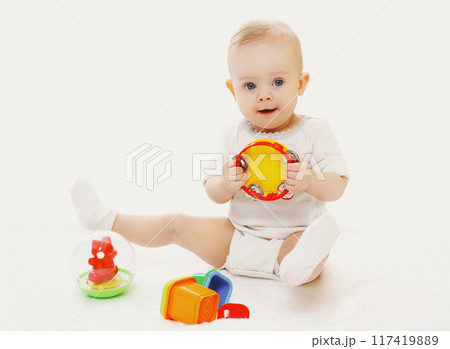 Happy little baby playing with toys sitting on white background Happy little baby playing with toys sitting on white background 117419889