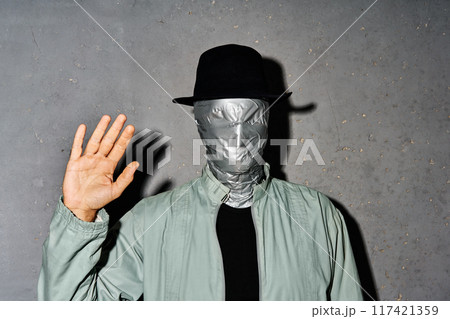 Mystery man with duct tape face raised hand in greeting 117421359