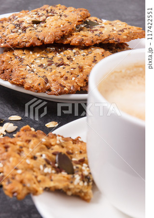 Cup of coffee with milk and homemade oatmeal cookies on white plate. Delicious crunchy dessert 117422551