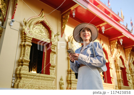 A woman wearing a straw hat is standing in front of a building with gold trim A woman wearing a straw hat is standing in front of a building with gold trim 117423858