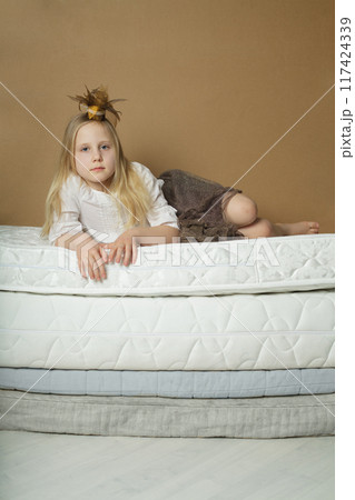 Cheerful young child girl lying on bed at home Cheerful young child girl lying on bed at home 117424339