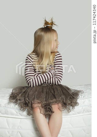 Cute young blonde girl looking away and sitting at home Cute young blonde girl looking away and sitting at home 117424340