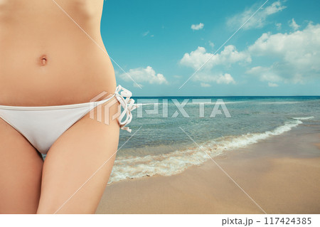 Woman relaxing on tropical resert. Hips bikini stomach abs close-up 117424385