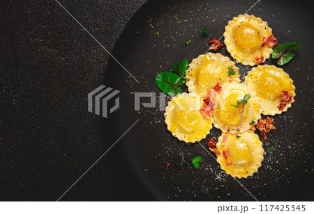 fresh ravioli, with butter, spices and herbs, fried bacon, on a black plate, top view, dark background, no people, fresh ravioli, with butter, spices and herbs, fried bacon, on a black plate, top view, dark background, no people, 117425345