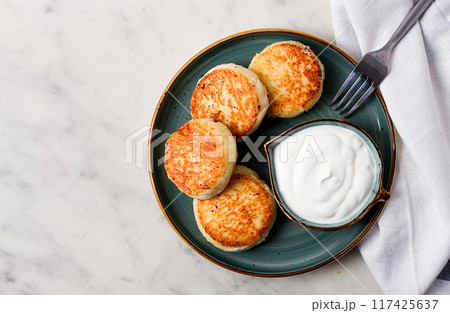 Fried, Cottage cheese pancakes, with sour cream, Cheesecakes, on a marble table, top view, no people. 117425637