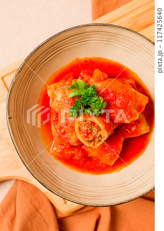 Stuffed cabbage rolls, with minced meat, in tomato sauce, on a beige background, top view, no people, selective focus. Stuffed cabbage rolls, with minced meat, in tomato sauce, on a beige background, top view, no people, selective focus. 117425640