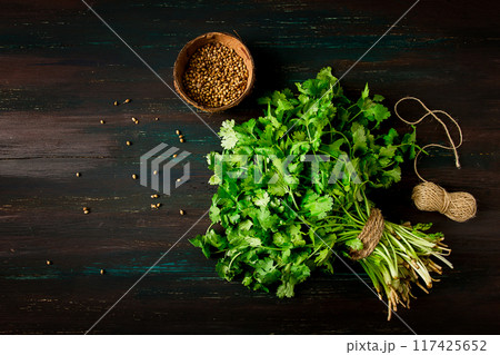 bunch of fresh Cilantro, coriander seeds, on a dark wooden table, close-up, top view, no people. bunch of fresh Cilantro, coriander seeds, on a dark wooden table, close-up, top view, no people. 117425652