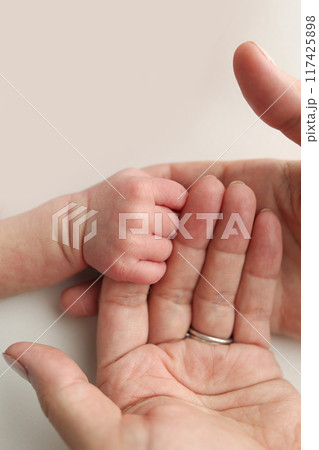 The newborn baby has a firm grip on the parent's finger after birth. Close-up little hand of child and palm of mother and father. Parenting, childcare and healthcare concept. 117425898