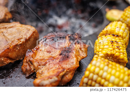Delicious meat steaks and vegetables on the grill in the garden close-up, Delicious meat steaks and vegetables on the grill in the garden close-up, 117426475
