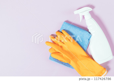 A bottle of cleaning spray sits next to a blue cloth and an orange glove A bottle of cleaning spray sits next to a blue cloth and an orange glove 117426786