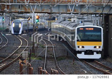 船橋駅を出た早朝の総武線を走る各駅停車と特急あずさの並走 117426981