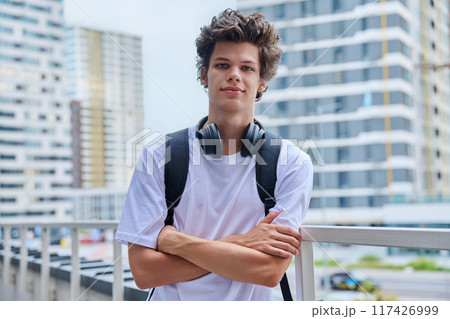 Handsome young man looking at camera outdoors, modern skyscrapers urban style background 117426999