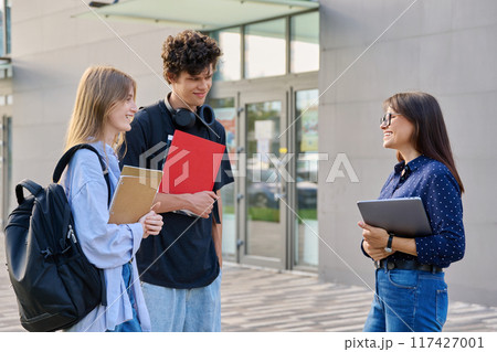 Group of college students talking with female teacher, educational building background 117427001