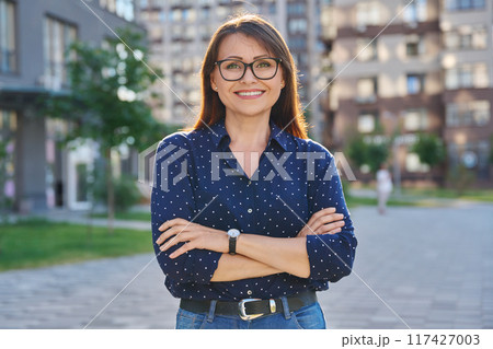 Portrait of middle-aged confident woman posing outdoors 117427003