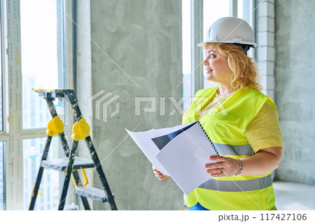 Technical profession woman in safety vest helmet working on construction Technical profession woman in safety vest helmet working on construction 117427106