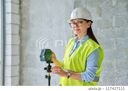 Woman industrial worker in protective vest helmet working on construction site Woman industrial worker in protective vest helmet working on construction site 117427111