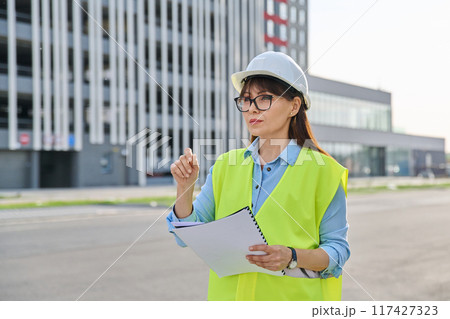 Industrial worker female builder with working documents, outdoor construction Industrial worker female builder with working documents, outdoor construction 117427323