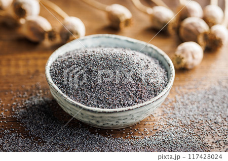 Dry head and poppy seed in bowl on kitchen table. 117428024