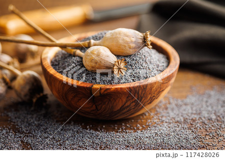 Dry head and poppy seed in bowl on kitchen table. 117428026
