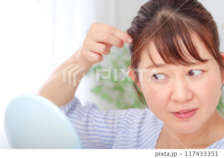 髪の毛をチェックしている40代の女性 髪の毛をチェックしている40代の女性 117433351