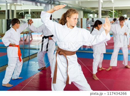 Girls in kimono standing in combat stance in gym Girls in kimono standing in combat stance in gym 117434266