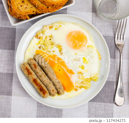 Fried eggs with onions served with sausage Fried eggs with onions served with sausage 117434271