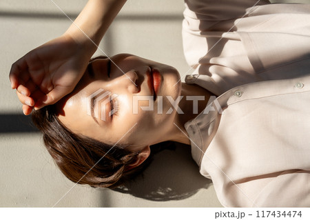 フローリングに寝転ぶミドル女性 117434474