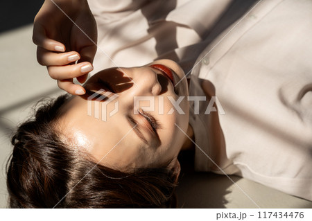 フローリングに寝転ぶミドル女性 117434476