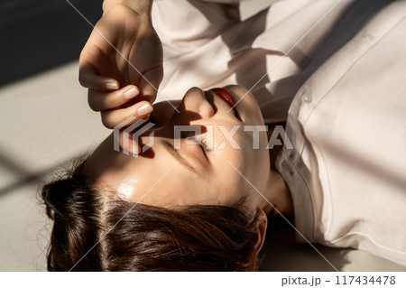 フローリングに寝転ぶミドル女性 117434478