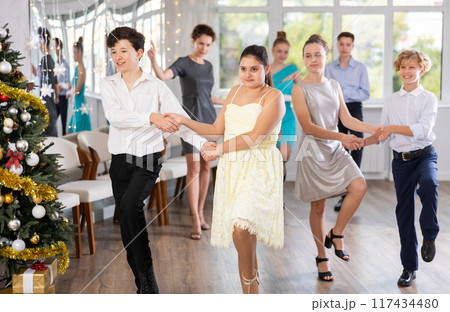 Celebrating Christmas in dance class - girls and boys dance the Moresco dance near New Year tree 117434480