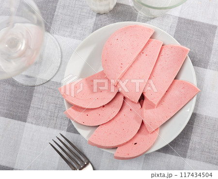 There are thick slices of boiled sausage on small round plate There are thick slices of boiled sausage on small round plate 117434504