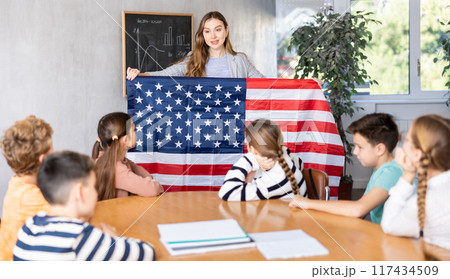 Teacher showing USA flag to group of schoolchildren 117434509