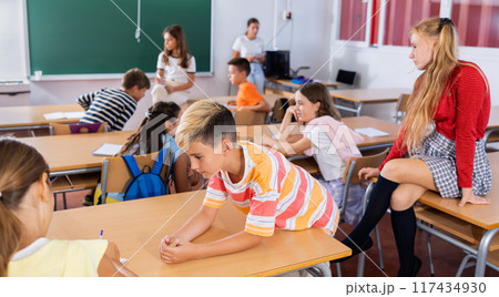 Schoolboy communicating with girl classmate at recess in class Schoolboy communicating with girl classmate at recess in class 117434930