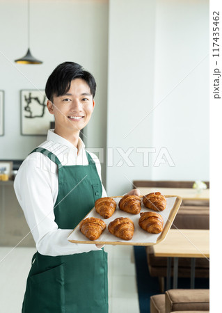 クロワッサンを勧める若い男性の店員 117435462