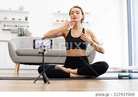 Woman practicing yoga and filming vlog at home Woman practicing yoga and filming vlog at home 117437009