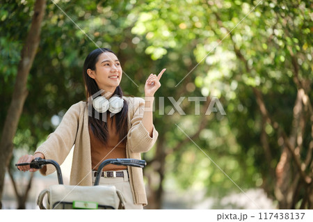 A woman in a wheelchair is pointing to something in the distance A woman in a wheelchair is pointing to something in the distance 117438137