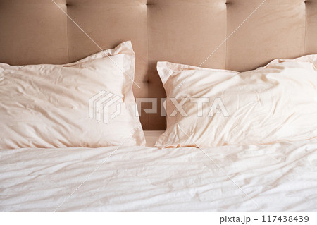 Messy bed with crumpled pillows and sheets on beige headboard. Messy bed with crumpled pillows and sheets on beige headboard. 117438439
