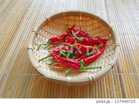 家庭菜園で収穫した赤唐辛子と竹カゴの写真 117440725