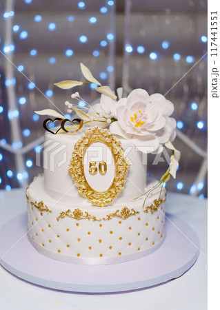 Beautiful white two-tiered cake decorated with flowers. 50th Anniversary Cake. 117441551