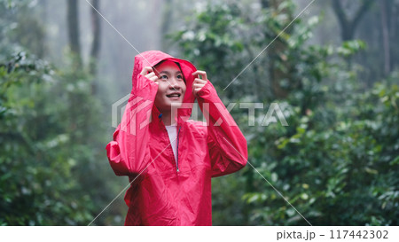 Smiling woman in red raincoat enjoying the forest Smiling woman in red raincoat enjoying the forest 117442302