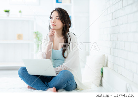 リビングでパソコンを使う若い女性 リビングでパソコンを使う若い女性 117443216