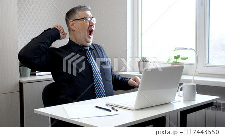 Tired Man Stretching and Yawning in Office Tired Man Stretching and Yawning in Office 117443550