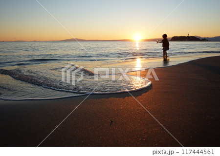 夕日に染まる波打ち際で遊ぶ子供 117444561