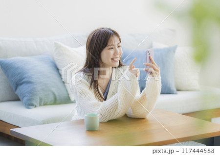 部屋でくつろぐニットの若い女性 117444588